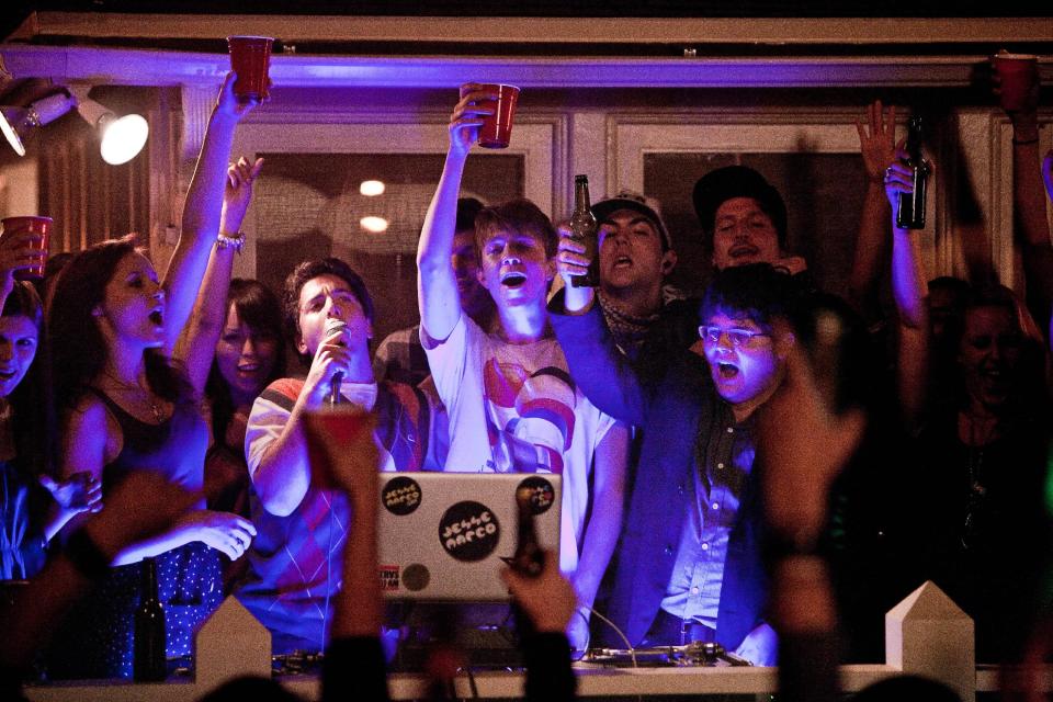 In this film image released by Warner Bros., from left, Oliver Cooper, with microphone, Thomas Mann and Jonathan Daniel Brown are shown in a scene from "Project X." (AP Photo/Warner Bros., Beth Dubber)