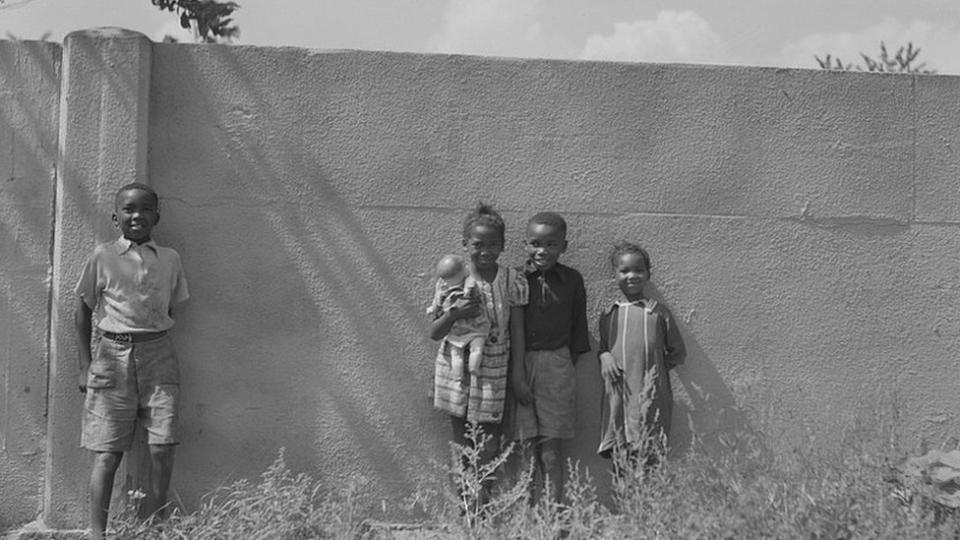 Niños negros apoyados en el muro