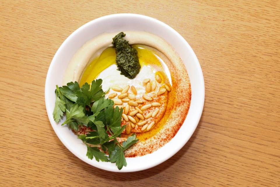 Top-down view of a bowl of hummus tahini on a wooden table.