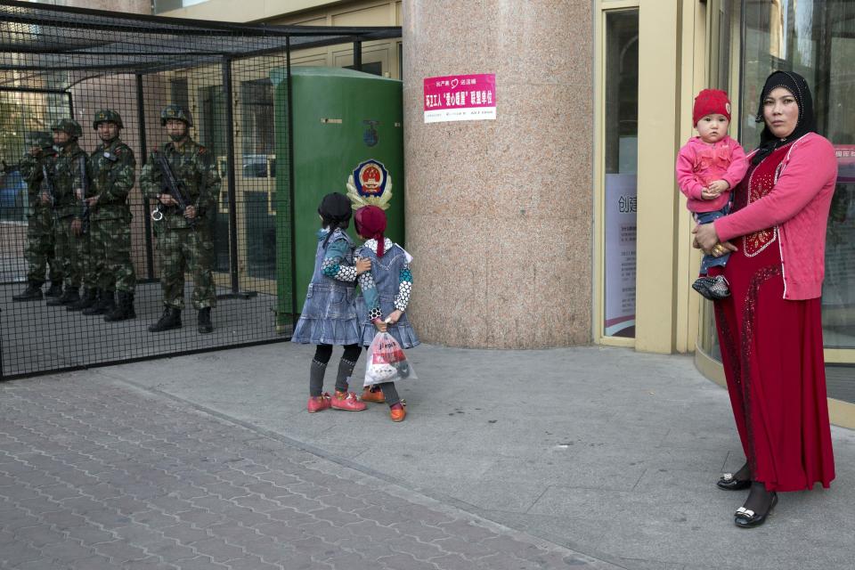 Uighur children play near a cage protecting heavily armed Chinese paramilitary policemen on duty in Urumqi in northwest China's Xinjiang Uygur Autonomous Region on Thursday, May 1, 2014. Recent deadly attacks in China blamed on Islamic extremists are getting bolder and bloodier, targeting civilians rather than the authorities and further challenging Beijing’s ability to stop them. (AP Photo/Ng Han Guan)