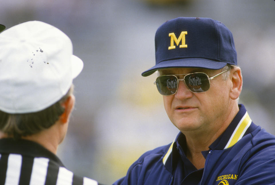 Michigan coach Bo Schembechler talks with an official while his team warms up before an NCAA football game in 1986. (Getty Images)