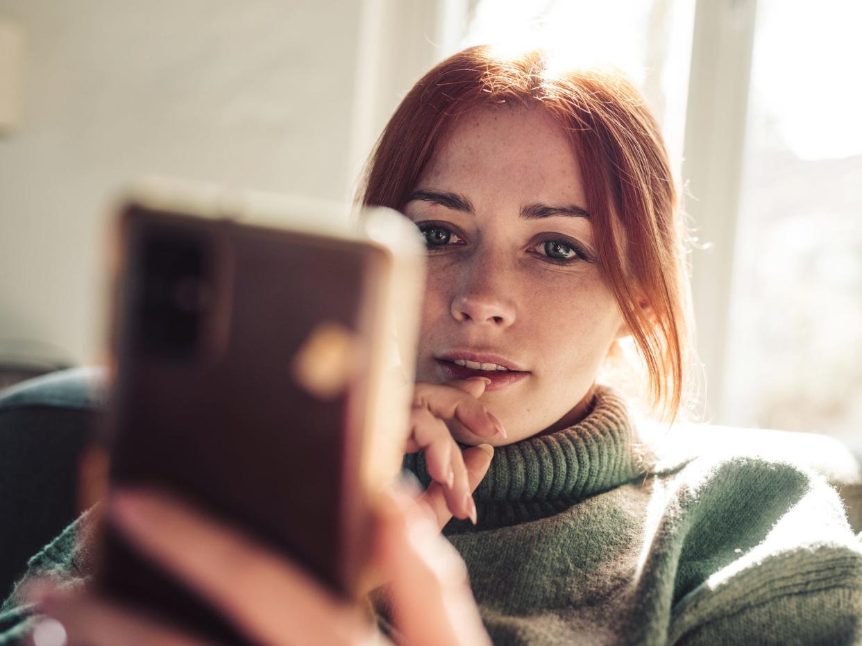 a redhead woman reads messages on her phone