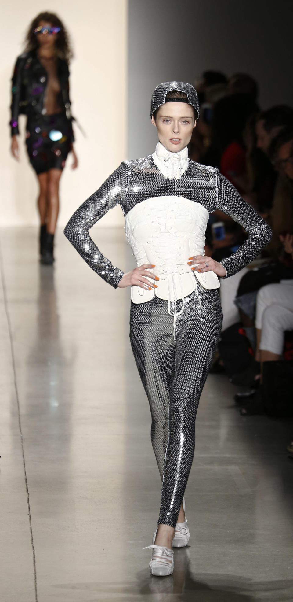 Coco Rocha wears a full sequin bodysuit, hat, and white corset at the Jeremy Scott show. (Photo: Getty)