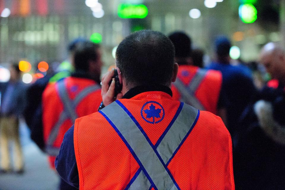 An Air Canada baggage handler talks on a cell phone during a a wildcat walkout at Toronto's Pearson International Airport early Friday March 23, 2012 causing some flights to be delayed. The job action began Thursday evening and left hundreds of passengers in limbo after they had to disembark from several flights already on the tarmac and head back to the terminal. (AP Photo/Victor Biro, The Canadian Press)