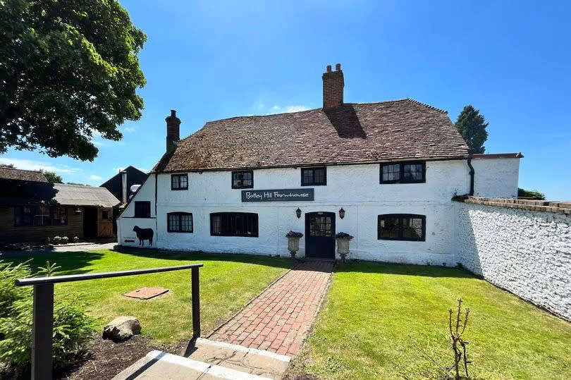 Photo of the Botley Hill Farmhouse pub front with a sign and small painting of a black sheep