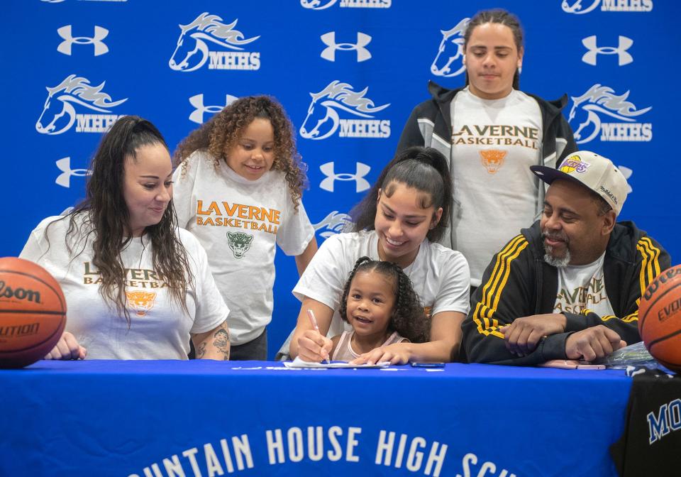 Mountain House girls basketball player Cayla Harang, center, is surrounded by her family, mother Cassie, left, sister Lanoua, 8, daughter Royalty, 3, brother Prayshawn, 14, and father Ronald during her signing a letter if intent to play for the University of La Verne during a ceremony at the high school in Tracy on Wednesday, Apr. 12, 2023.