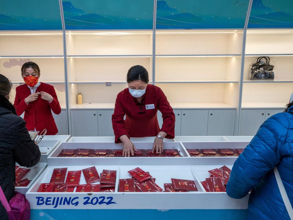 Clerks stand in front of empty shelves as customers look at a display case at the official Beijing 2022 Winter Olympics flagship souvenir store on February 8, 2022 in Beijing, China. Crowds of people have been lining up at authorized Beijing 2022 Winter Olympic stores trying to purchase Bing Dwen Dwen paraphernalia, the panda mascot of the Games. Items featuring the character have become a hot seller that Beijing 2022 merchandise stores cannot keep them in stock. Officials say the factories authorized to produce the souvenirs have been urged to increase production to help boost supplies. The sudden popularity of Bing Dwen Dwen, along with the Paralympic Games mascot Shuey Rhon Rhon, comes as most Chinese fans are unable to attend Olympics events in the host city because of China's zero-COVID protocols.