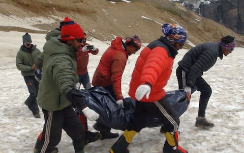 Indian Border Patrol agents carry the body of a mountaineer from Nanda Devi to a waiting helicopter - Credit: AFP