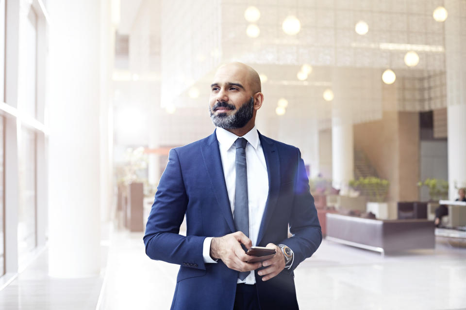 A man in a business suit holding his phone