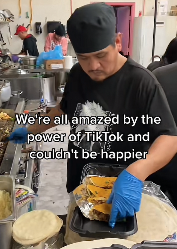 kitchen worker putting tacos into a take-out box