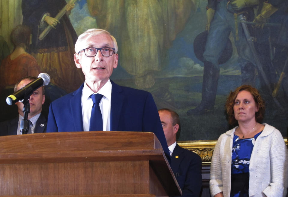 FILE - In this June 20, 2019, file photo, Wisconsin Gov. Tony Evers is surrounded by Democratic lawmakers and members of his Cabinet at a Capitol news conference in Madison, Wis. The Wisconsin Institute for Law and Liberty filed a lawsuit Wednesday, July 31, 2019, on behalf of three taxpayers, asking the Wisconsin Supreme Court to dramatically scale back the ability of governors to change the intent of lawmakers through partial budget vetoes. It is the most aggressive challenge yet to vetoes made by Evers to the state budget approved by the Republican-controlled Legislature in late June. (AP Photo/Scott Bauer, File)
