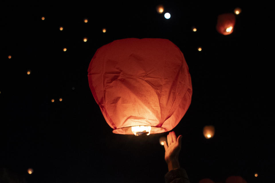 A reveler releases a sky lantern at Kotzia square, in central Athens, Greece, on Christmas Eve, Sunday, Dec. 24, 2023.(AP Photo/Michael Varaklas)