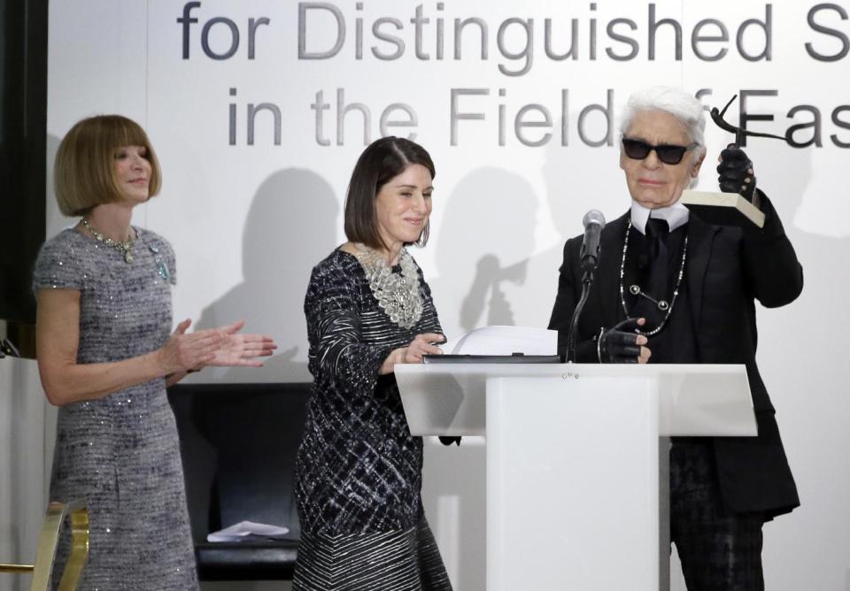 Anna Wintour, left, editor-in-chief of Vogue and Karen Katz, president and CEO of Neiman Marcus applaud as Chanel designer Karl Lagerfeld holds up his fashion award during an ceremony at the department store, Wednesday, Dec. 11, 2013, in Dallas. (AP Photo/Tony Gutierrez)