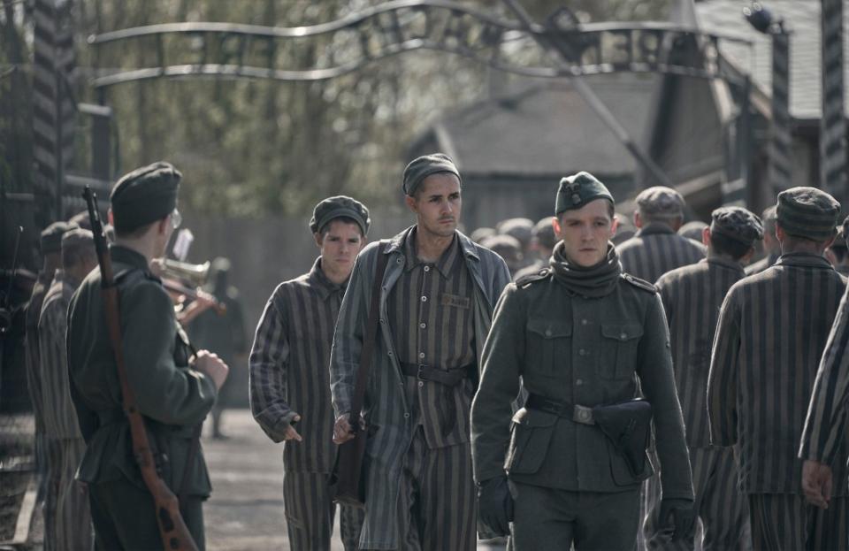 Jonah Hauer-King as Lali Sokolov seen here walking through Auschwitz with German-born actor Jonas Nay as Nazi officer Stefan Baretzki, front right