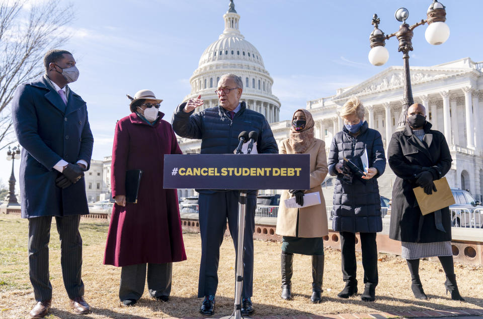 Senate Majority Leader Sen. Chuck Schumer of N.Y., center, at a podium with a sign saying 