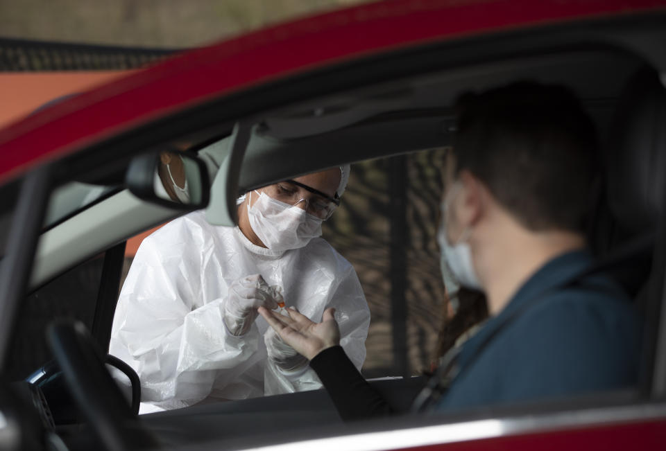 A health worker collects a sample from a person at a drive-thru test site for COVID-19 amid the new coronavirus pandemic in Niteroi, Brazil, Wednesday, June 3, 2020. (AP Photo/Silvia Izquierdo)