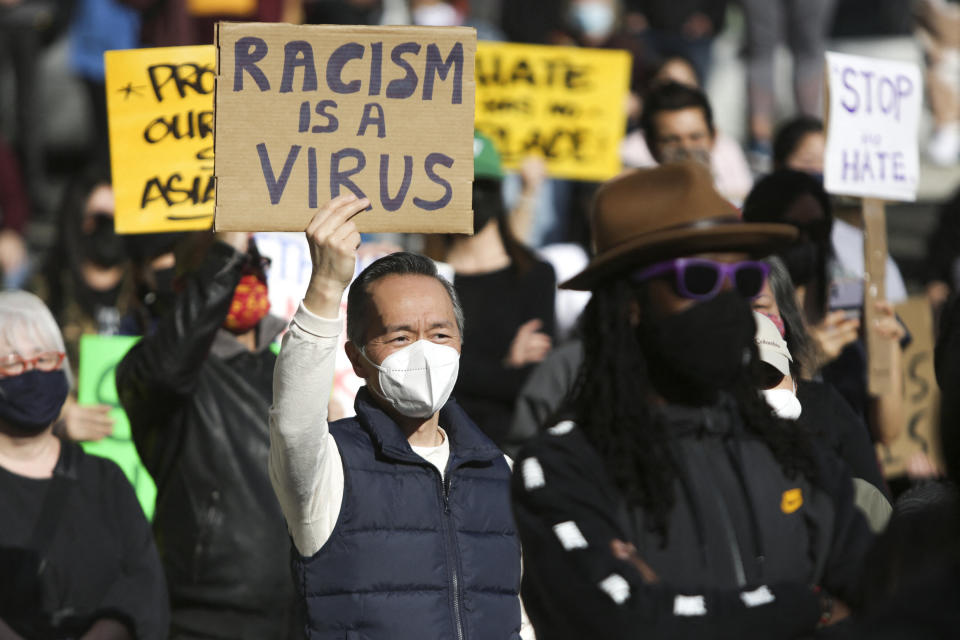 A man holds a sign that reads "Racism is a Virus" during the "We Are Not Silent" rally against anti-Asian hate in response to recent anti-Asian crime in the Chinatown-International District of Seattle, Washington, on March 13. (Photo: JASON REDMOND via Getty Images)