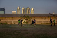 Thai man, some with face masks play a game of soccer in an open lot in Bangkok, Thailand, Wednesday, April 8, 2020. Playgrounds and public parks remained closed as a month-long state of emergency has been enforced in Thailand to allow its government to impose stricter measures to control the coronavirus that has infected hundreds of people in the Southeast Asian country. (AP Photo/Gemunu Amarasinghe)