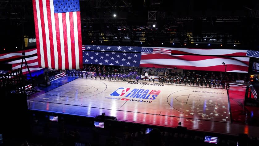 Los Angeles Lakers and Miami Heat players pause for the national anthem prior to the first half of Game 1 of basketball's NBA Finals Wednesday, Sept. 30, 2020, in Lake Buena Vista, Fla. (AP Photo/Mark J. Terrill)