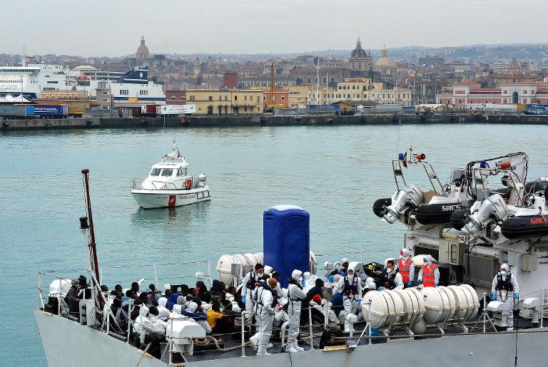 Rescued migrants wait to disembark an Italian Guardia Costiera vessel at the Sicilian harbour of Catania on April 24, 2015