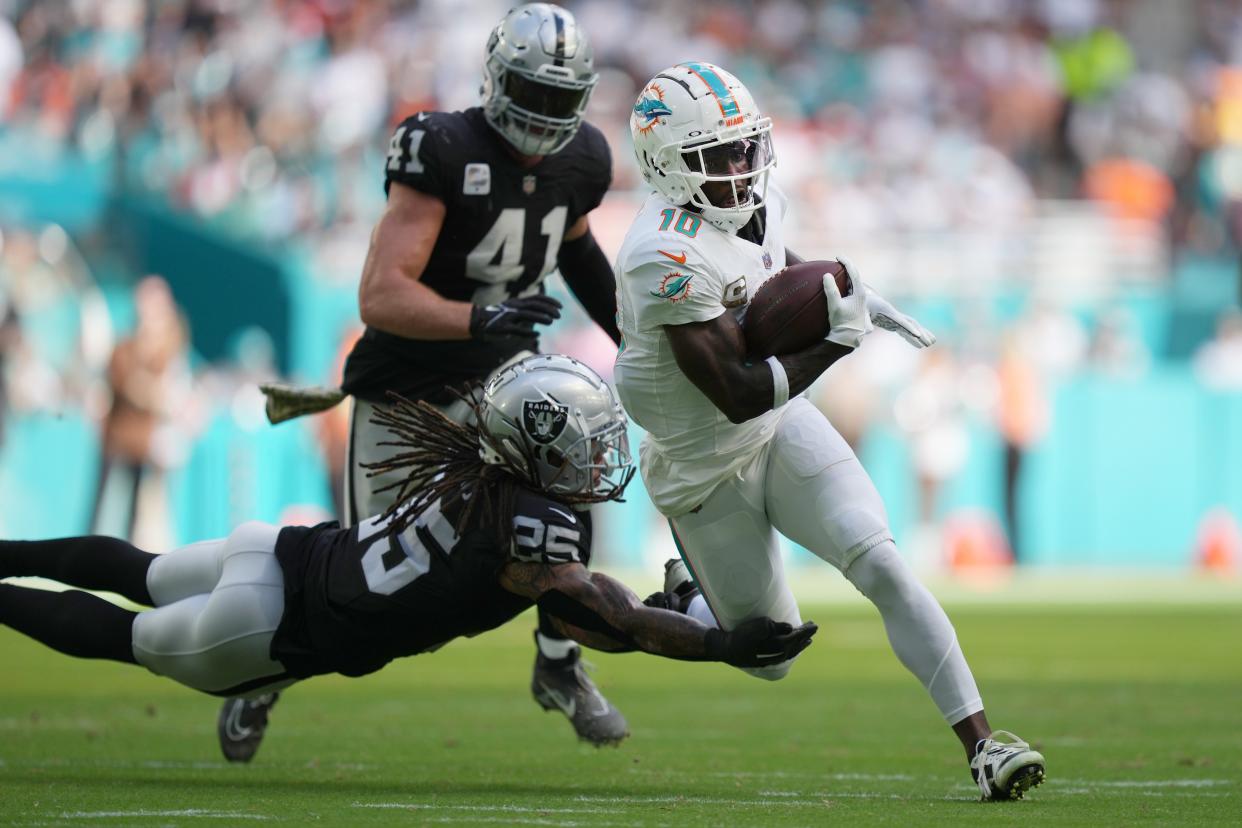 Miami Dolphins wide receiver Tyreek Hill (10) breaks the tackle of Las Vegas Raiders safety Tre'von Moehrig (25) and scores a touchdown during the first half of an NFL game at Hard Rock Stadium in Miami Gardens, Nov. 19, 2023.