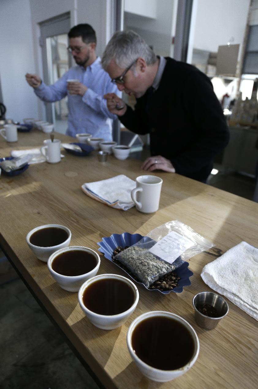 In this photo taken Thursday, Jan. 3, 2013, James Freeman, right, founder of Blue Bottle Coffee cups coffee samples, observing the tastes and aromas of brewed coffee from Uganda at his roastery in Oakland, Calif.