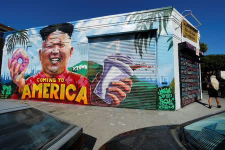 A woman uses a phone to take a picture of a mural showing North Korean leader Kim Jong Un painted on the side of a building in the Koreatown neighborhood of Los Angeles, California, U.S., June 11, 2018. REUTERS/Mike Bake