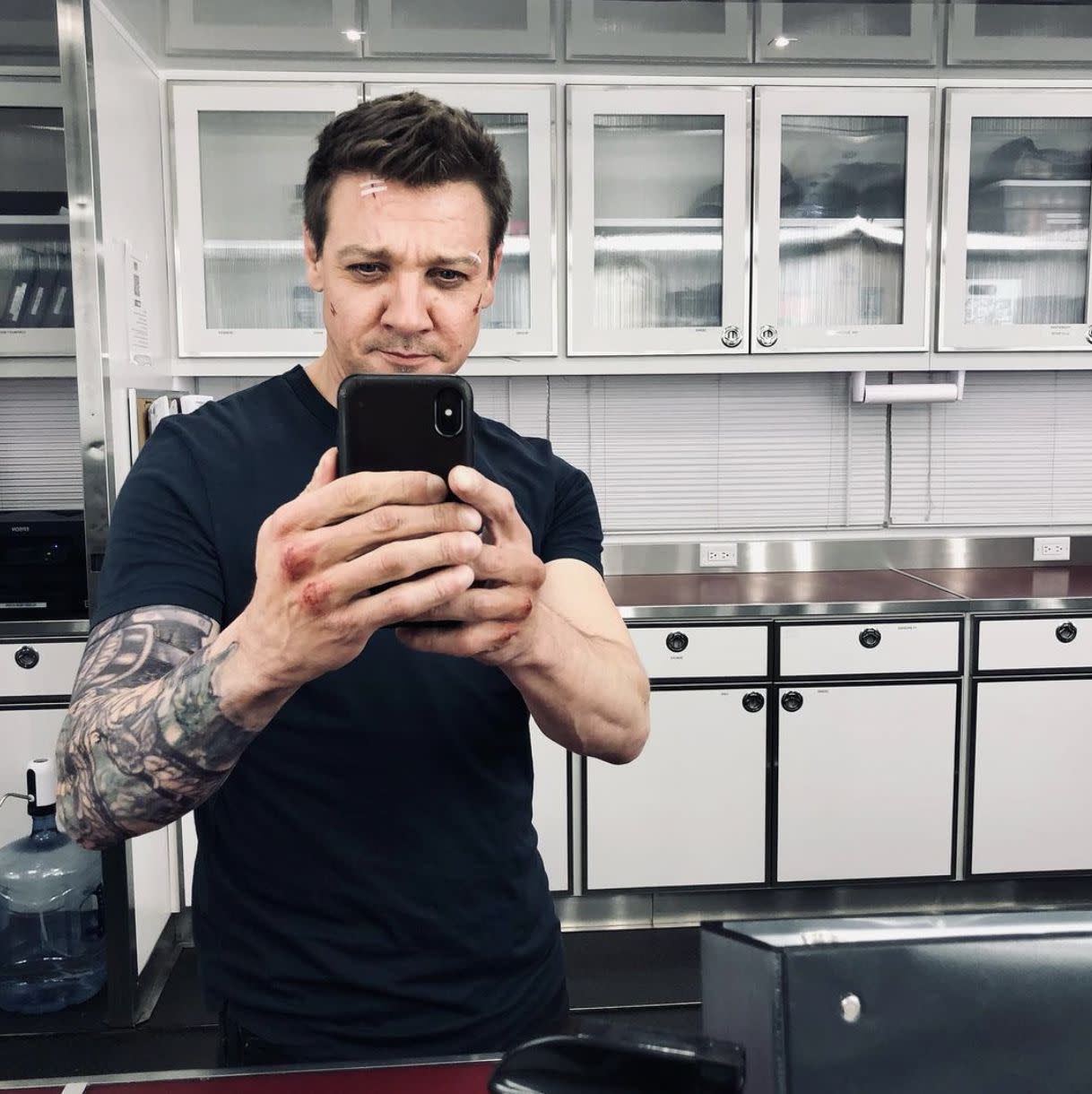 Jeremy Renner sports cuts and bruises while filming on set for the upcoming Disney+ show "Hawkeye." The 50-year-old actor captioned the behind-the-scenes snap: "At least it’s not Monday"