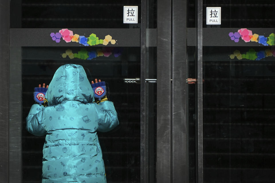 A child peeps into a shuttered shopping mall as part of COVID-19 controls in Beijing, Thursday, Dec. 1, 2022. More cities eased anti-virus restrictions as Chinese police tried to head off protests Thursday while the ruling Communist Party prepared for the high-profile funeral of the late leader Jiang Zemin. (AP Photo/Andy Wong)