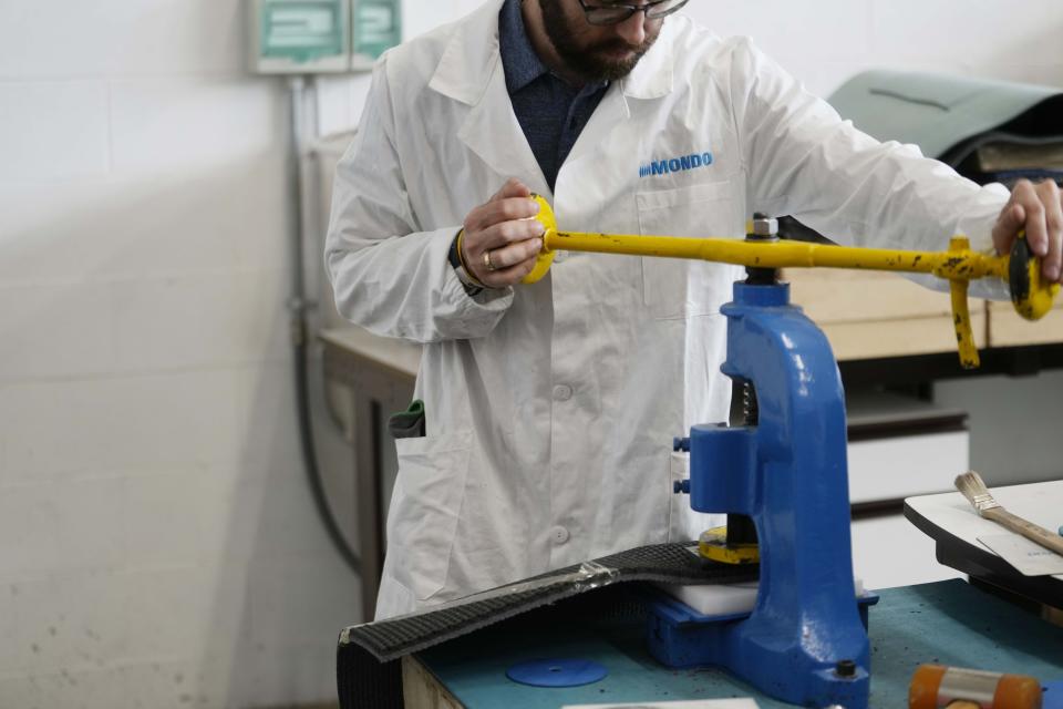 A worker checks a piece of the athletics track, at the Mondo factory, in Alba, northern Italy, Wednesday, March 13, 2024. The athletics track for the upcoming Paris Olympics is being produced by the Mondo company at its factory in northern Italy. The track is made in portions, rolled up and then will be transported to the Stade de France, where it will be installed over the next month. (AP Photo/Luca Bruno)