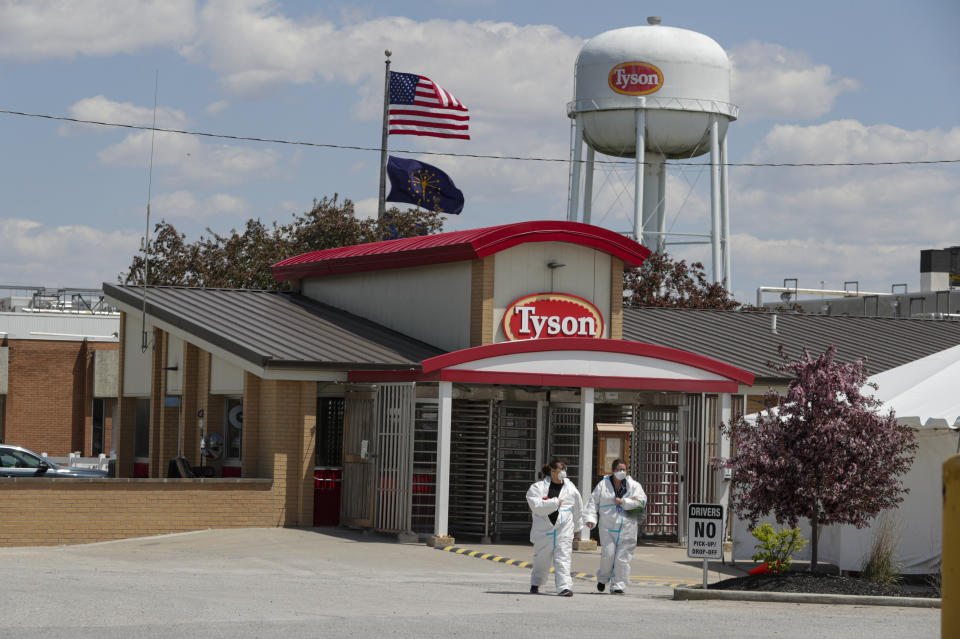 FILE - In this May 7, 2020 file photo, workers leave the Tyson Foods pork processing plant in Logansport, Ind. For the first time in two years for many people, the American workplace is transforming into something that resembles pre-pandemic days. The U.S. has since seen COVID-19 infections and hospitalizations plummet. Cases have plunged from 455,000 a day two weeks ago to 150,000 on Monday, Feb. 14, 2022. (AP Photo/Michael Conroy, File)