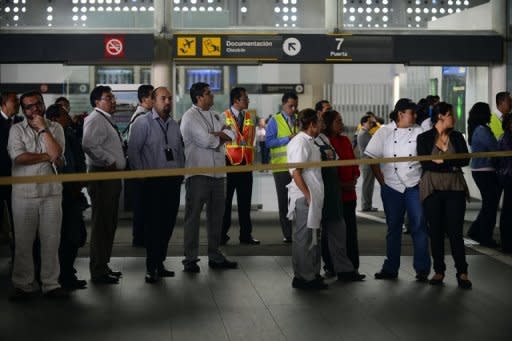 Airport employees wait near the fast-food area of Benito Juarez international airport Terminal 2, in Mexico City, after three police officers were shot dead in a shootout with alleged drug traffickers on June 25, 2012