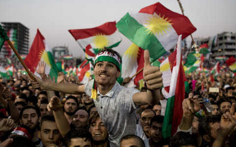 Supporters wave flags and chant slogans inside the Erbil Stadium while waiting to hear Kurdish President Masoud Barzani speak - Credit: Chris McGrath/Getty Images