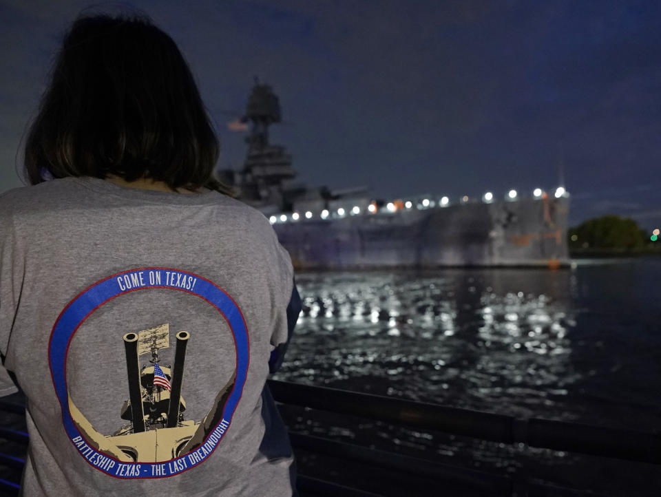 Michelle Austin watches as the USS Texas is moved from the dock Wednesday, Aug. 31, 2022, in La Porte, Texas. The vessel, which was commissioned in 1914 and served in both World War I and World War II, is being towed down the Houston Ship Channel to a dry dock in Galveston where it will undergo an extensive $35 million repair. (AP Photo/David J. Phillip)