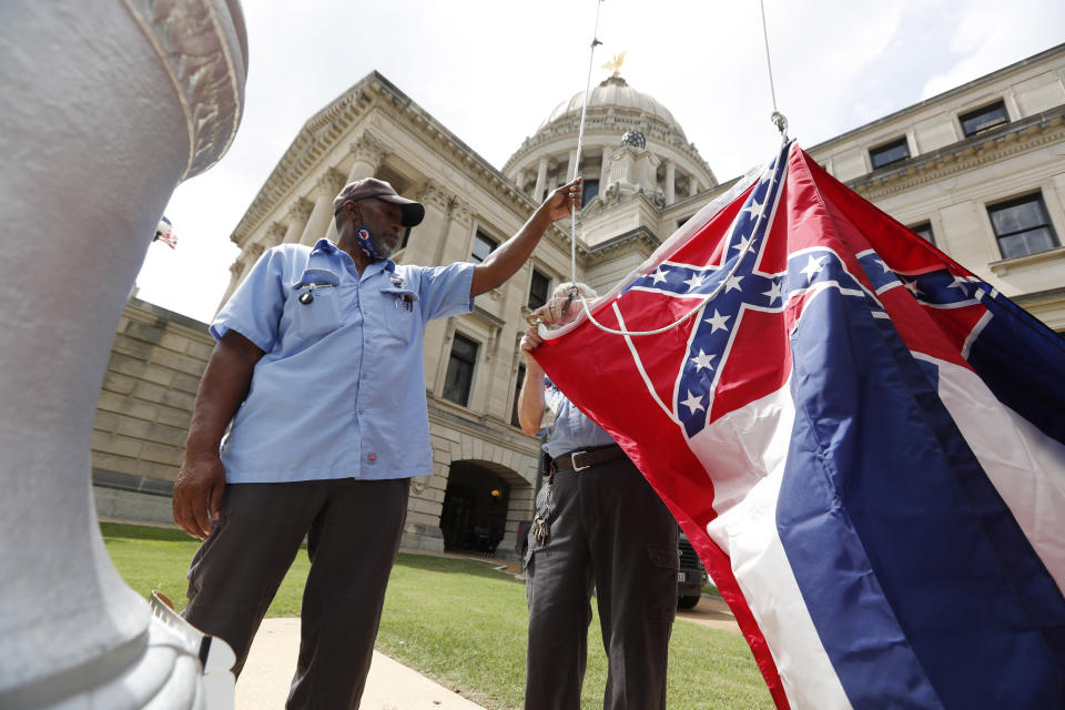 Mississippi Department of Finance and Administration employees Willie Townsend, left, and Joe Brown, attach a Mississippi state flag to the harness before raising it over the Capitol grounds in Jackson, Miss., Tuesday, June 30, 2020. The two men raised about 100 flags, provided by the Secretary of State's office, for people or organizations that purchased a state flag that flew over the grounds. Gov. Tate Reeves will sign a bill Tuesday evening retiring the last state flag with the Confederate battle emblem during a ceremony at the Governor's Mansion. Upon the governor signing the bill, the flag will lose its official status. (AP Photo/Rogelio V. Solis)