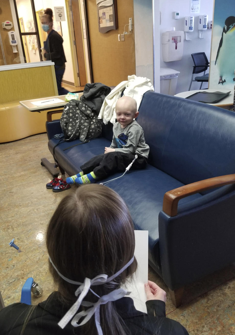 In this April 1, 2020 photo provided by The Valerie Fund, Child Life specialist Jillian Hinko reads an encouraging email written by 15-year-old Sarah Schneider to patient Jacen Stout, 2, who's receiving treatment at the Newark Beth Israel Valerie Fund Center in Newark, N.J. (Courtesy of The Valerie Fund via AP)