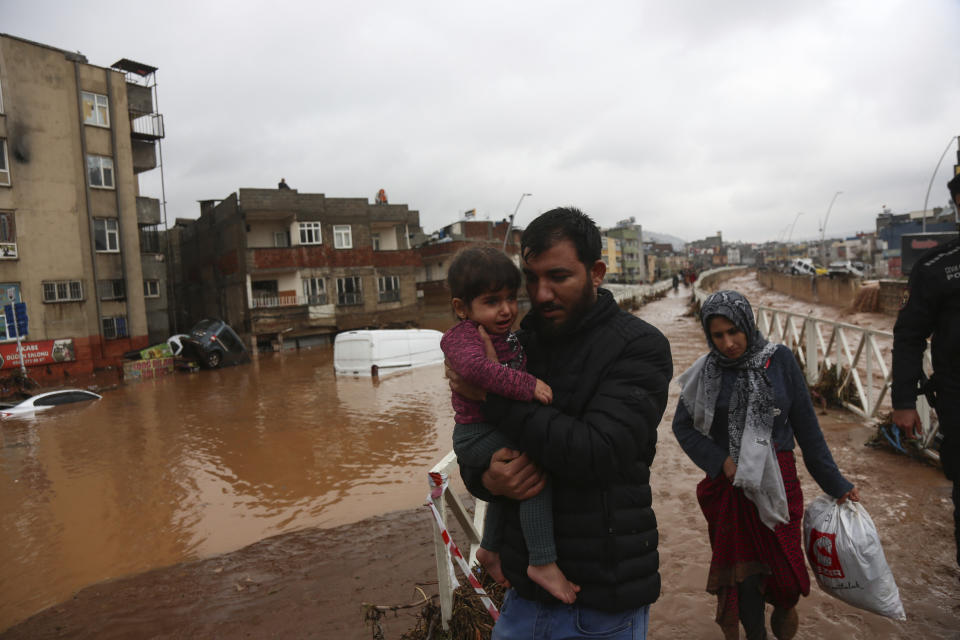 People leave during floods after heavy rains in Sanliurfa, Turkey, Wednesday, March 15, 2023. Floods caused by torrential rains hit two provinces that were devastated by last month's earthquake, killing at least 10 people and increasing the misery for thousands who were left homeless, officials and media reports said Wednesday. At least five other people were reported missing. (Hakan Akgun/DIA via AP)