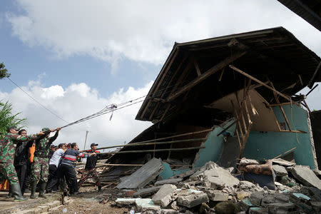 Security personnel and rescue workers pull the remains of a building down following yesterday's 4.4 magnitude quake in Kertosari Village, Banjarnegara, Central Java, Indonesia April 19, 2018 in this photo taken by Antara Foto. Antara Foto/Idhad Zakaria / via REUTERS