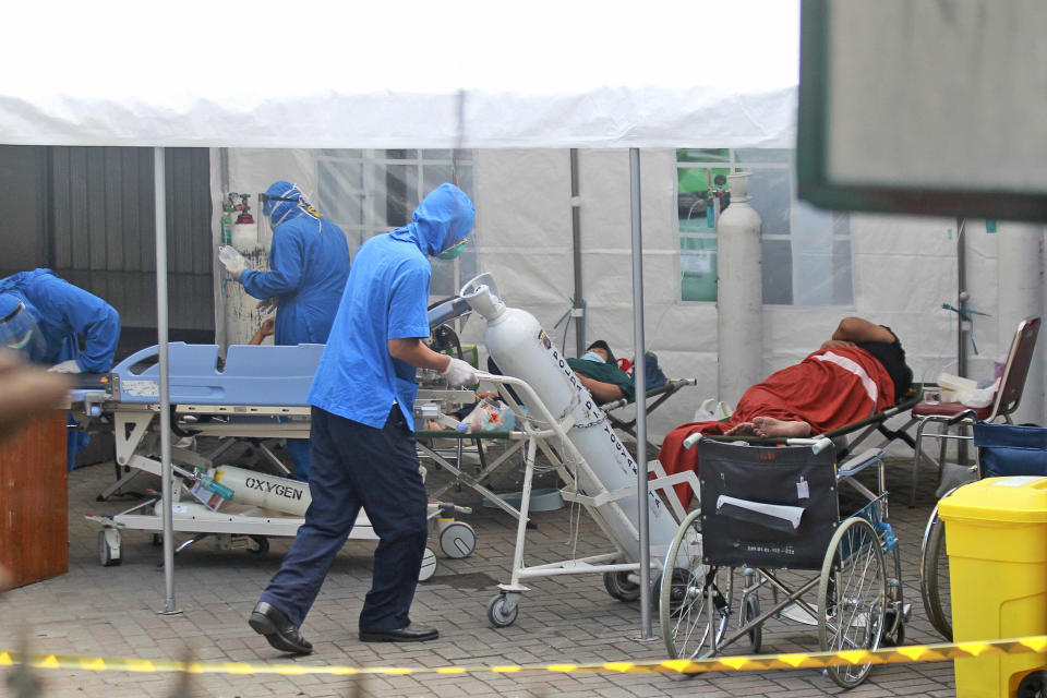 A medical worker wheels an oxygen tank to be used to treat patients at an emergency tent erected to accommodate a surge in COVID-19 cases, at Dr. Sardjito Central Hospital in Yogyakarta, Indonesia, Sunday, July 4, 2021. A number of COVID-19 patients died amid an oxygen shortage at the hospital on the main island of Java following a nationwide surge of coronavirus infections. (AP Photo/Kalandra)