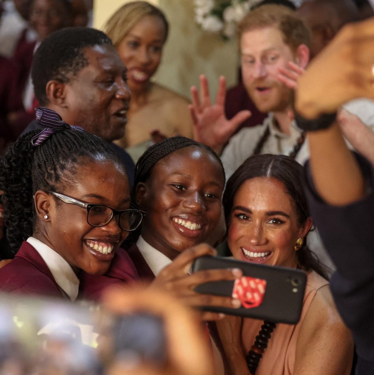Britain's Meghan, Duchess of Sussex (1st row 2nd R), takes a selfie with students as she arrives with Britain's Prince Harry, Duke of Sussex, during their visit at the Lightway Academy in Abuja on May 10, 2024 as they visit Nigeria as part of celebrations of Invictus Games anniversary.