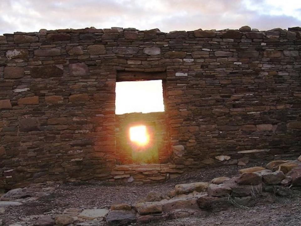 The sun shines through an opening in a wall made of bricks in the castle in Chaco canyon on solstice morning.