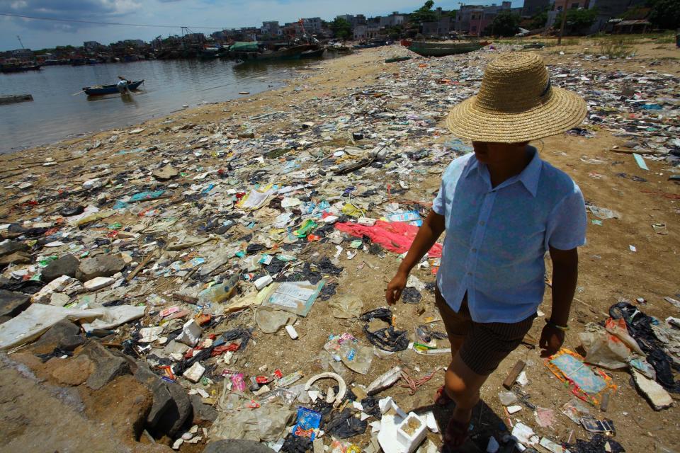 <p>A Chinese farmer walks along a garbage-strewn beach in Anguan village, Hainan, China, on June 13, 2011.</p>