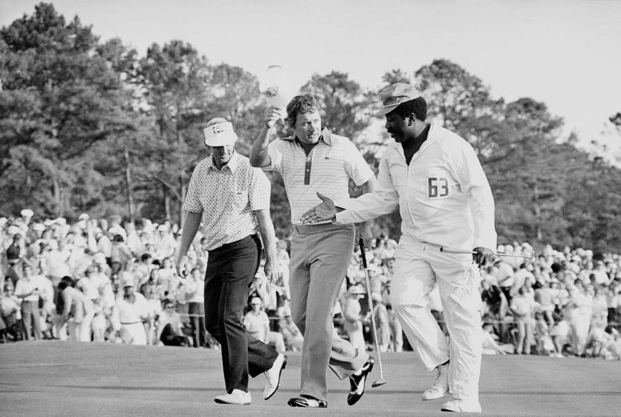 Golfer Ray Floyd, center, doffs his visor as caddie Hop Harris reaches over to shake hands after Floyd won the Masters Championship on Sunday, April 11, 1976 at Augusta, Ga. The man on the left is unidentified. (AP Photo)