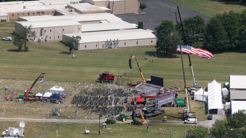 PHOTO: The stage where former President Donald Trump had been standing during an assassination attempt the day before, and the roof of a nearby building where a gunman was shot dead by law enforcement, in Butler, Pennsylvania, July 14, 2024.   (Brendan Mcdermid/Reuters)