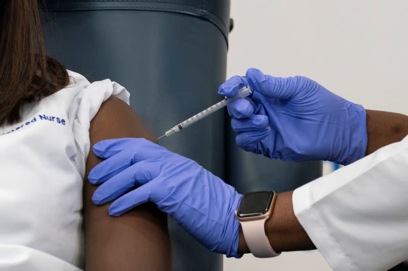 Sandra Lindsay, a nurse at Long Island Jewish Medical Center, is inoculated with the coronavirus disease (COVID-19) vaccine by Dr. Michelle Chester from Northwell Health at Long Island Jewish Medical Center in New Hyde Park, New York