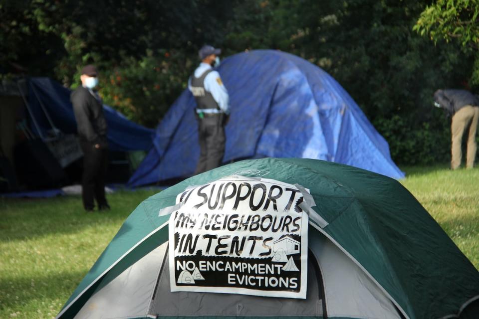 Police clear out a homeless encampment in Trinity Bellwoods Park, morning of Tuesday, 22-Jun, 2021. Protesters surround tents in an attempt to prevent police from removing the encampment.