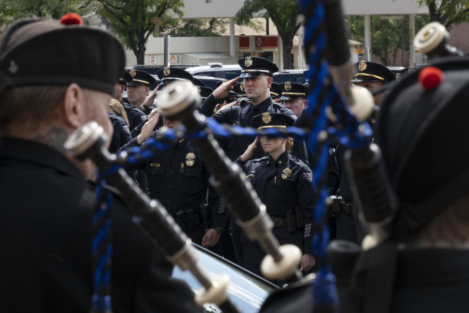 Arvada Police officers salute as the Arvada Firefighters Pipes and Drums play following the memorial service for fallen Arvada Police Officer Dillon Vakoff on Friday, Sept. 16, 2022, at Flatirons Community Church in Lafayette, Colo. Vakoff was fatally shot while trying to break up a large family disturbance earlier in the week, in Arvada. (Timothy Hurst/The Gazette via AP)