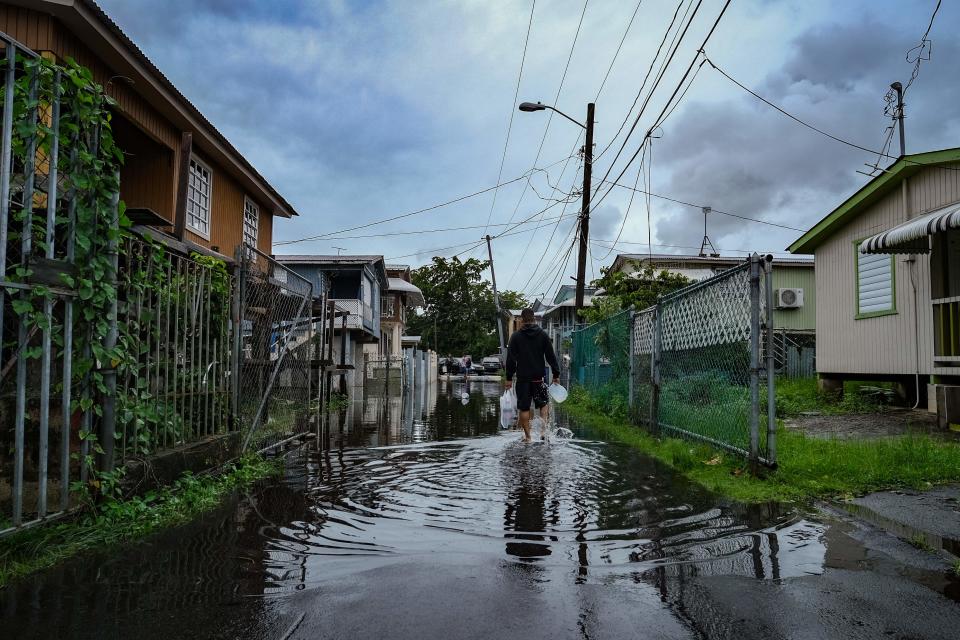 A man walks down a flooded street in the Juana Matos neighborhood of Catano, Puerto Rico, on Sept. 19, 2022, after the passage of Hurricane Fiona.