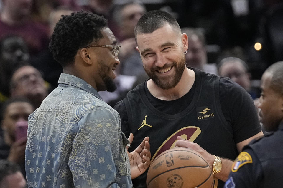 Injured Cleveland Cavaliers guard Donovan Mitchell, left, talks with Travis Kelce, right, during a time out in the second half of an NBA basketball game against the Boston Celtics, Tuesday, March 5, 2024, in Cleveland. (AP Photo/Sue Ogrocki)