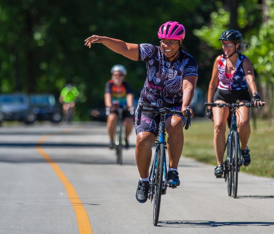 A participant waves to supporters who cheer her on during the end of her race at the 3rd Annual Solidarity Ride at Shawnee Park in Louisville, Kentucky on June 18, 2022. 
